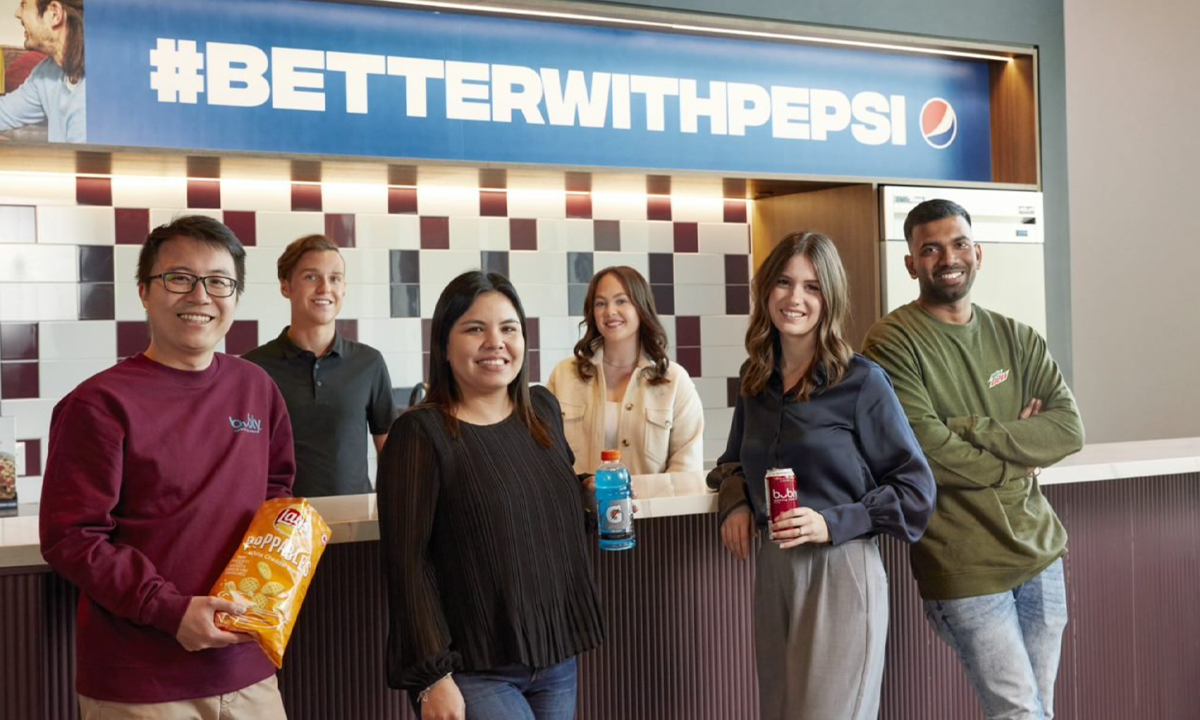 Employees by a #BetterWithPepsi sign holding PepsiCo products