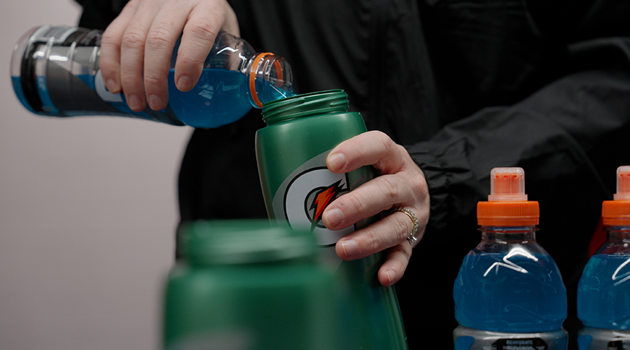 Une athlète verse la boisson sportive Gatorade dans la bouteille à système personnalisée Gx, conçue pour fournir une hydratation personnalisée en fonction des résultats des tests de sueur individuels et des besoins de remplacement en électrolytes.